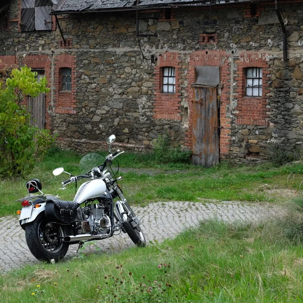 Classy motorbike parked in front of an old building in rural area.