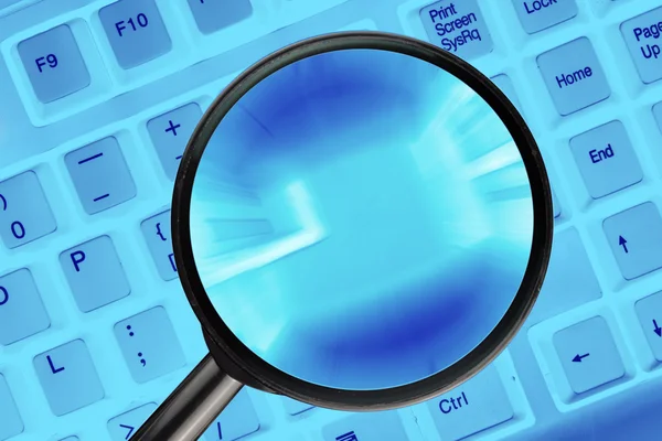 Magnifying glass on computer keyboard.