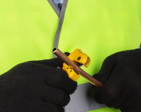 Master cutting a copper pipe with a pipe cutter