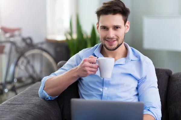 男子坐在沙发上用的笔记本电脑 - 图库照片pik