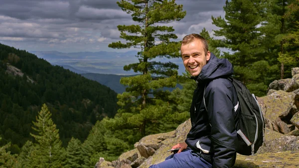 A young traveler man sit on the top of mountain in Prespa National Park  and enjoy the beauty of landscape near Bitola City.