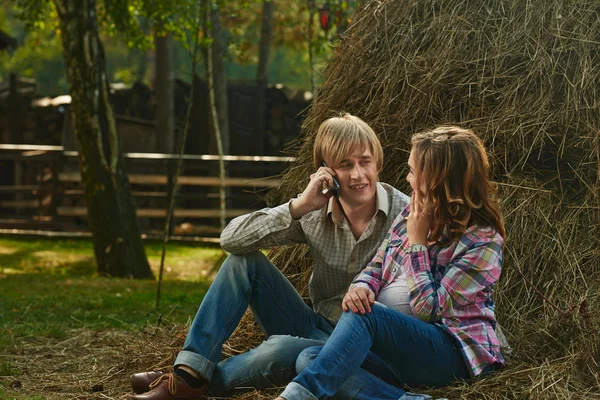 Couple talking by phone near haystack