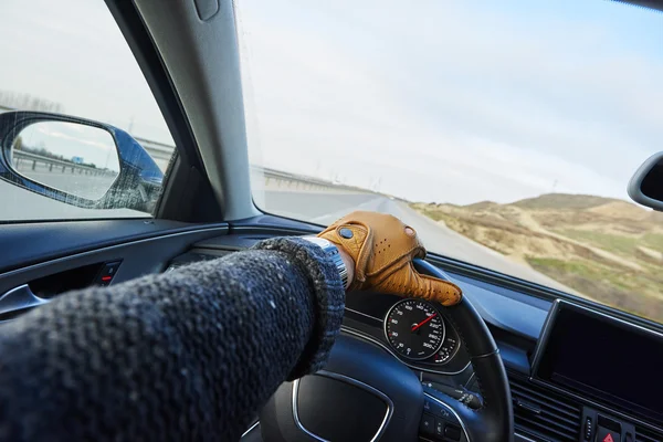 Close up of Driver\'s hand in the leather glove in the modern luxury car interior when speeding