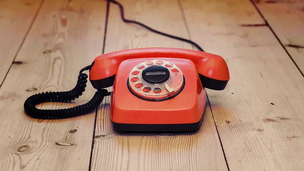 Red dial phone on a wooden background