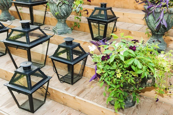 Iron lanterns for candles and flowers in pots on the steps of wo