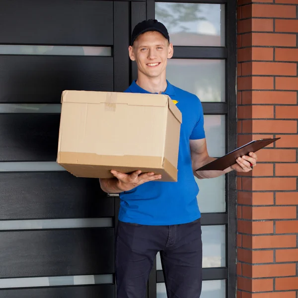 Smiling courier holding cardboard box