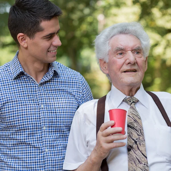 Male volunteer supporting old man