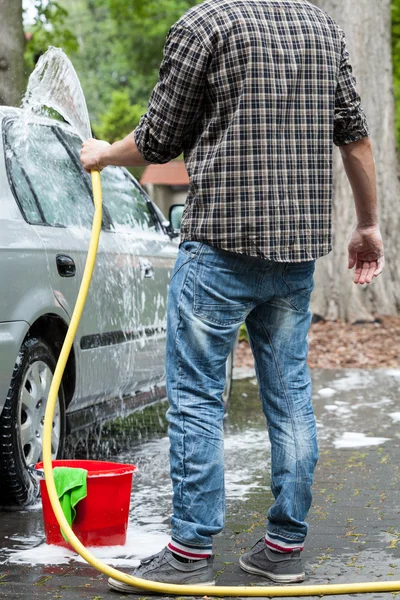 Man using garden hose for cleaning