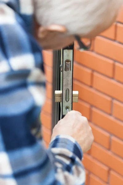 Older man repairing a door lock