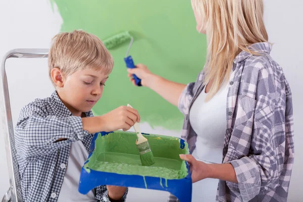 Son helping his mother painting a wall