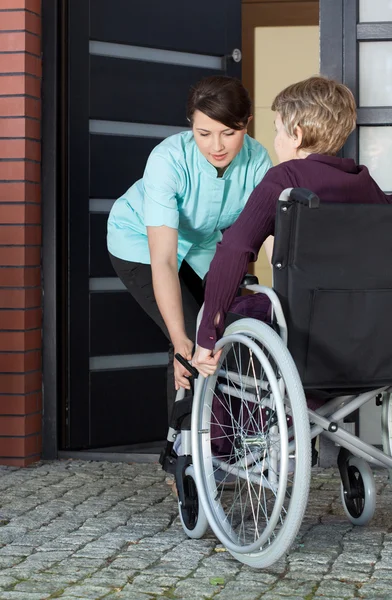 Caregiver helping disabled woman entering home