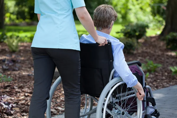 Nurse pushing elderly woman on wheelchair