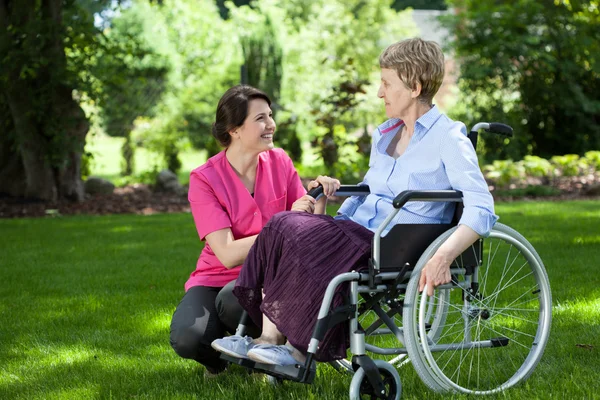 Senior woman on wheelchair with caring caregiver