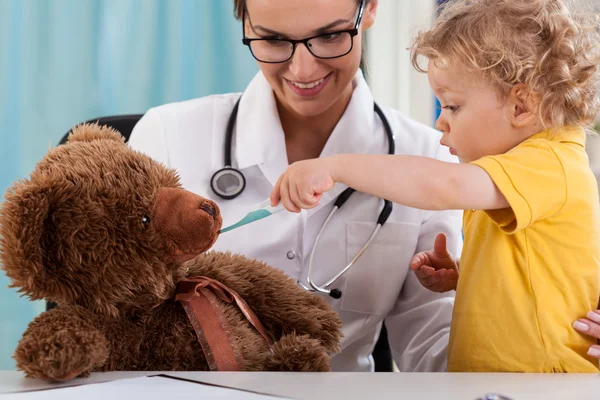 Child taking temperature of teddy bear