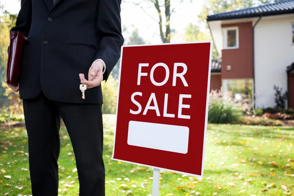 Estate agent with keys and sign