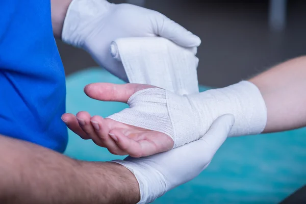 Male doctor bandaging a hand
