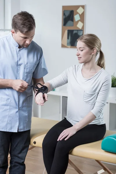 Physiotherapist putting orthosis on hand