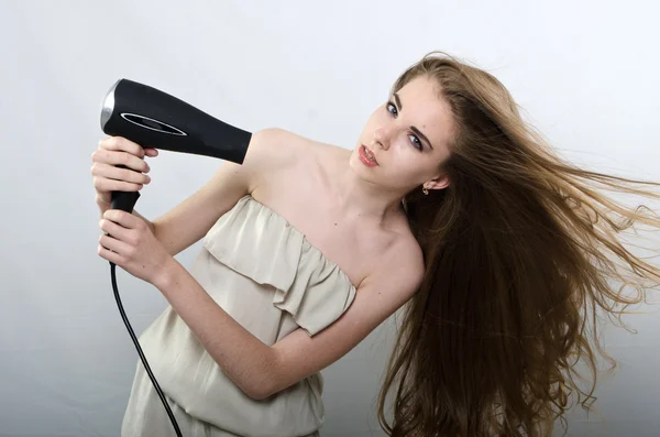 The girl plays with the hair dryer with hair