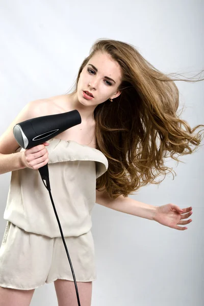 The girl plays with the hair dryer with hair