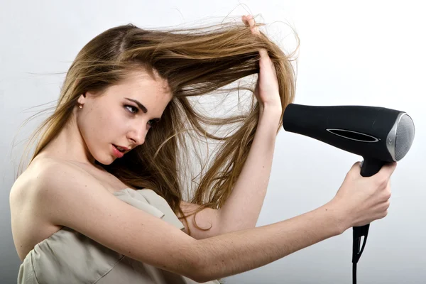 The girl plays with the hair dryer with hair