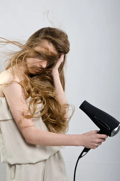 The girl plays with the hair dryer with hair