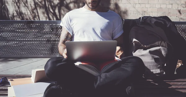 Photo man sitting city park bench and using laptop wireless internet. Studying at the University, working new project. Using book, generic design computer. Horizontal