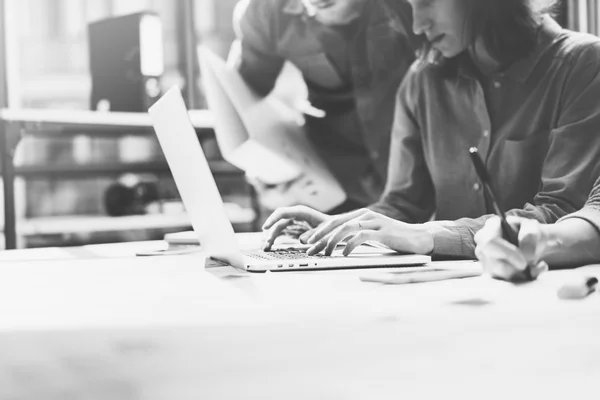 Team job. Photo young businessmans crew working with new startup project in modern loft. Generic design notebook on wood table. Horizontal, film effect, black and white