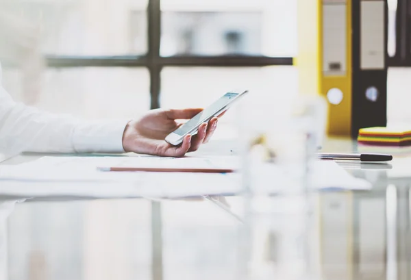 Photo woman working new startup project modern office. Contemporary smartphone holding female hands, message screen.Analyze statistics,plans table.Horizontal, film effect. Blurred