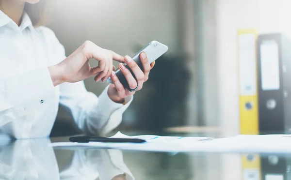 Photo young businesswoman working new startup project modern office.Contemporary smartphone holding female hands and touching screen.Analyze statistics.Horizontal, film effect. Blurred