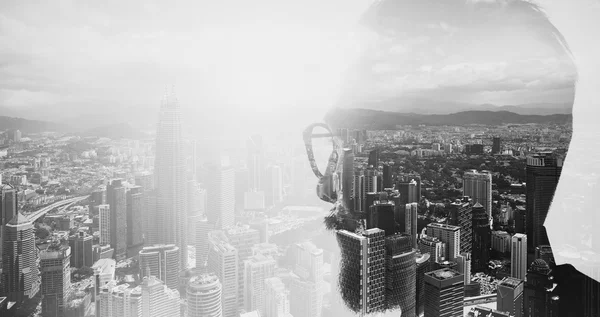 Closeup photo of stylish bearded banker wearing glasses and looking city. Double exposure, panoramic view contemporary megalopolis background. Space for your business message. Wide, black white.