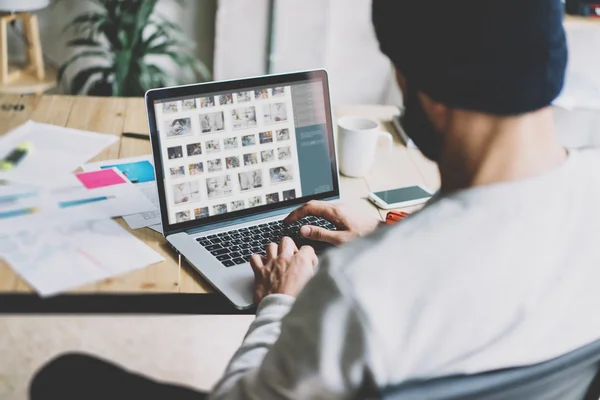 Photo bearded graphic designer working with new project modern loft. Contemprary notebook on wood table.  Images screen, hands typing keyboard. Freelance world. Blurred background, film effect