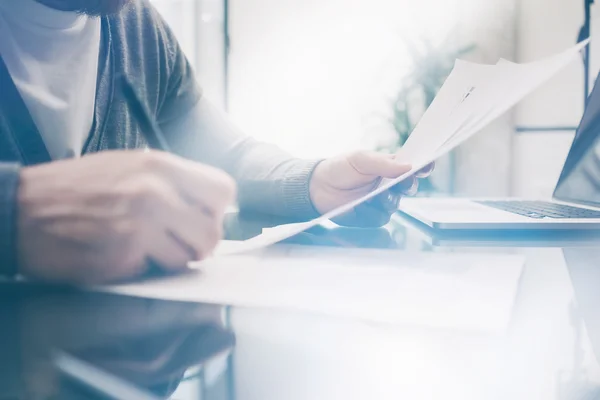 Closeup photo adult finance manager working at the table with new business project. Modern notebook on table. Signs document and analyze contracts. Horizontal, blurred, film effect