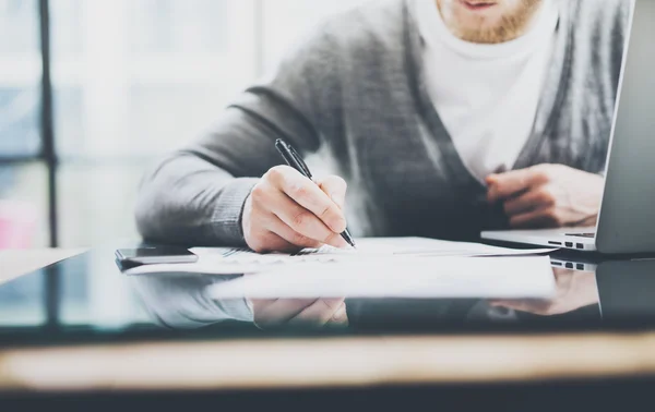 Working process photo. Manager working table with new startup project. Modern notebook table. Using pen for sign contract. Horizontal. Flares, film effect. Blurred background