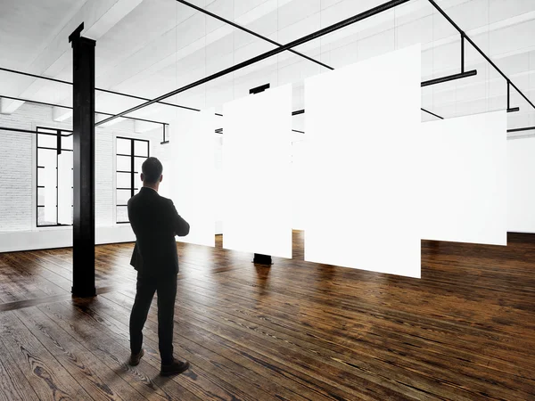 Gentleman Modern art museum expo loft interior.Open space studio.Empty white canvas hanging.Wood floor,bricks wall,panoramic windows.Blank frames ready for bussiness information.Horizontal mockup.