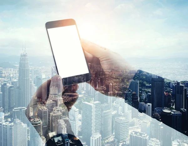 Double exposure photo modern smartphone holding male hands. Panoramic view contemporary city and clouds background. White blank screen ready for your business information.Horizontal mockup.