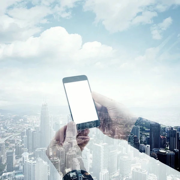 Double exposure photo modern smartphone holding male hands. Panoramic view contemporary city and clouds background. White blank screen ready for your business information.Square mockup.