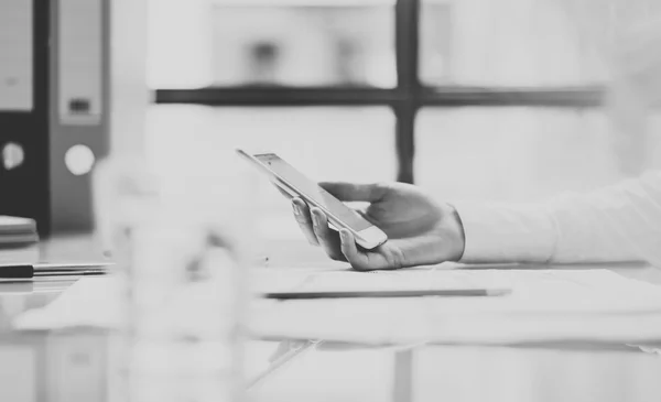 Photo business woman wearing white shirt, holding smartphone hands. Modern loft office studio. Black . Blurred background. Horizontal picture. Film effect.