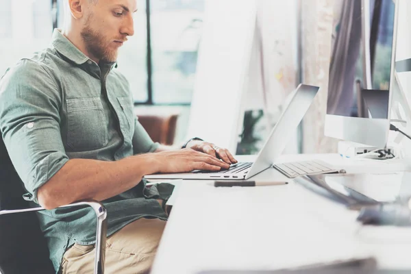 Bearded Hipster working Laptop modern Interior Design Loft Office.Man Work Coworking Studio,Use contemporary Notebook,typing keyboard.Blurred Background.Creative Business Startup Idea.Horizontal,Fil