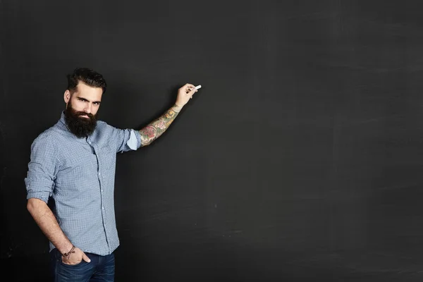 Bearded man draws on chalkboard