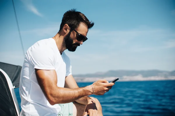 Man looking in his smartphone on the boat