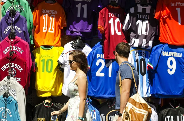 Boyfriend  watching football shirts on display