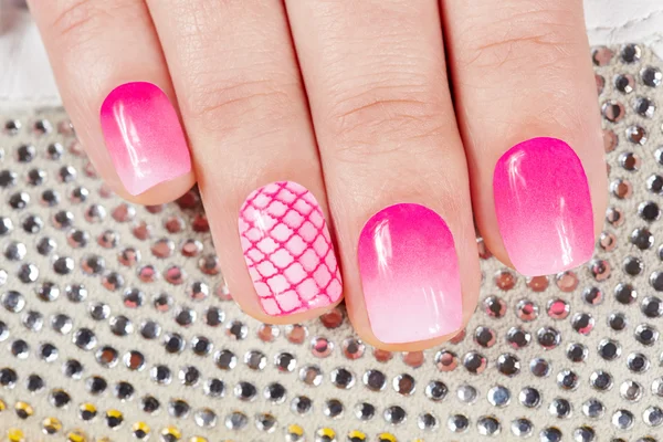 Nails with manicure covered with pink nail polish on crystals background