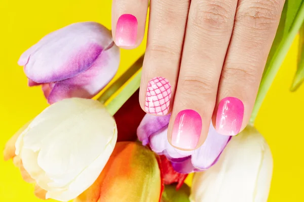 Hand with manicured nails and tulip flowers