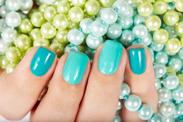 Nails with manicure on colored pearls background