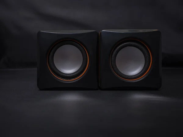 Black mini audio speakers on black background.