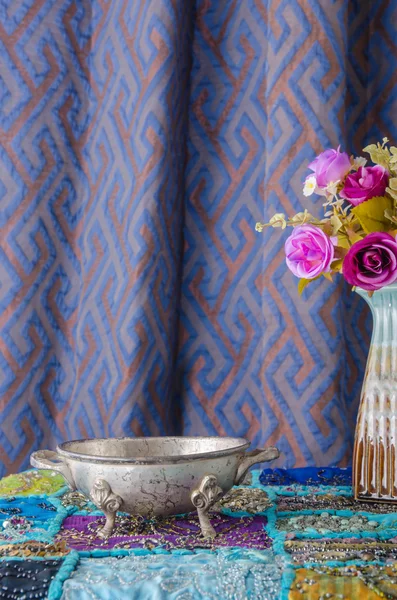 Moroccan metal bowl placed on a table with a vase of flowers.