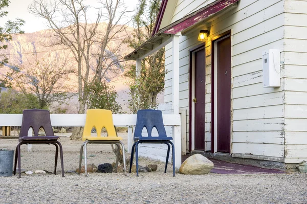 Small cottage house with 3 chairs in front of it.