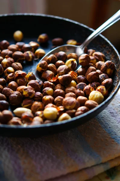 Roasted dried hazelnuts on iron pan with spoon