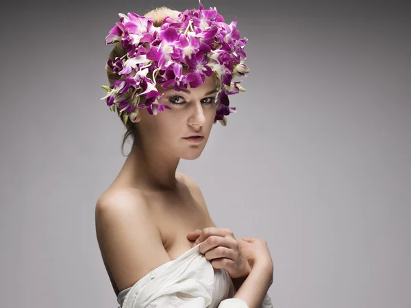 Portrait of attractive woman with orchids in her hairstyle.