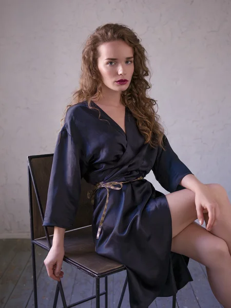 Woman in silk bathrobe sitting on a chair